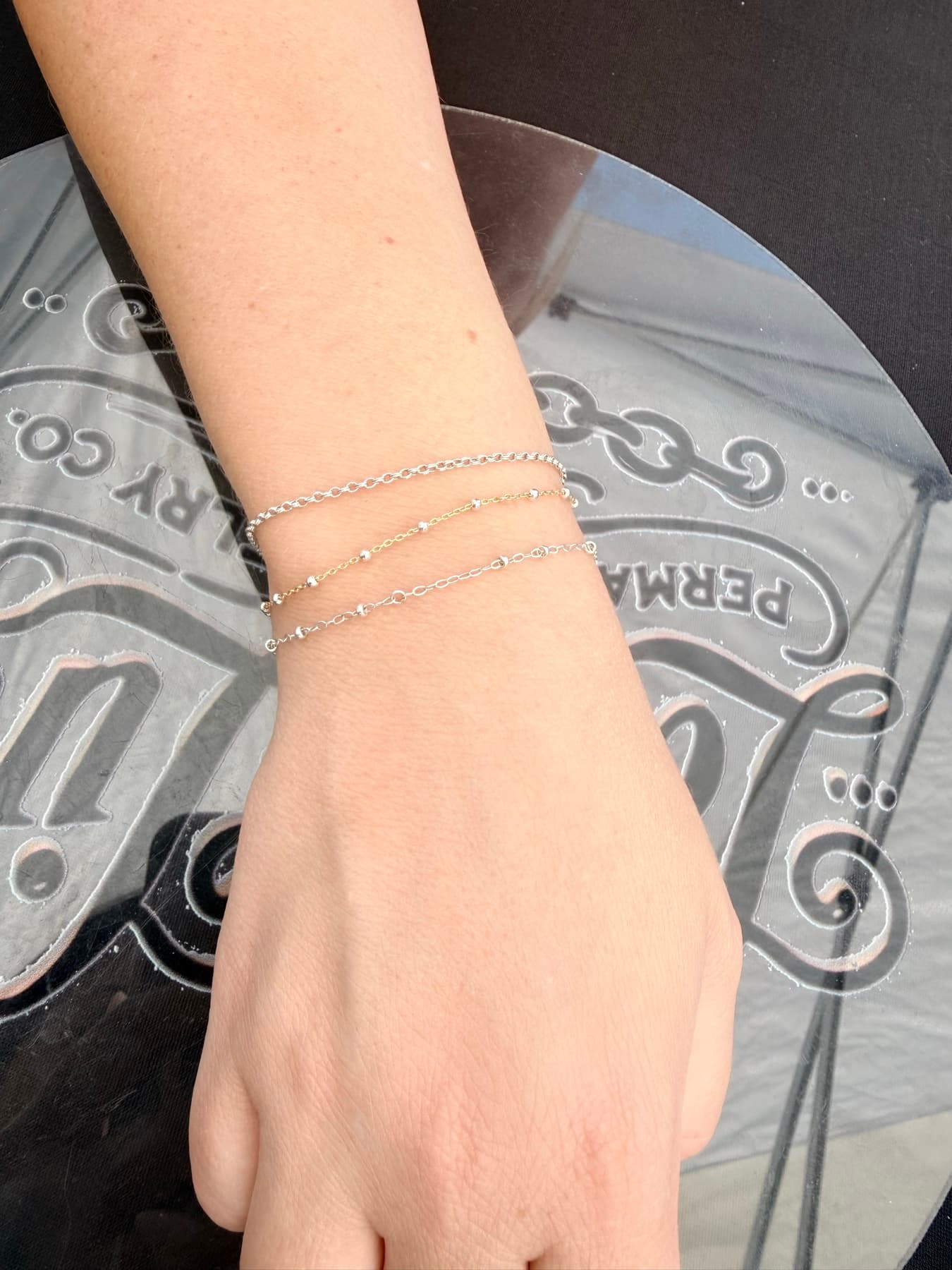 Three fine permanent bracelets on a wrist